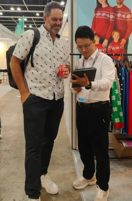A buyer reviewing Christmas knit styles with our team at a trade-fair booth